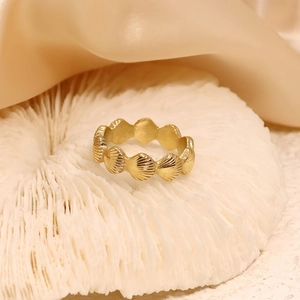 Détail d'une bague dorée texturée coquillage sur corail blanc et tissu en soie