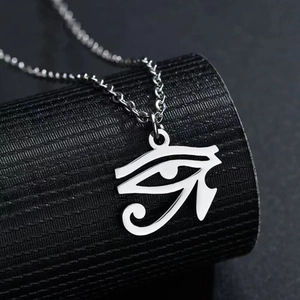 Détail macro du pendentif Œil d'Horus argenté avec chaîne à boules sur socle noir