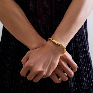 Vue détaillée d'un bracelet gourmette tissé doré porté au poignet avec fermoir chic