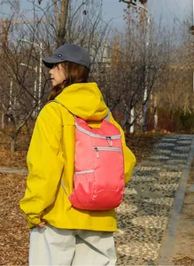 Pink lightweight foldable backpack made of water-resistant nylon worn by a hiker outdoors