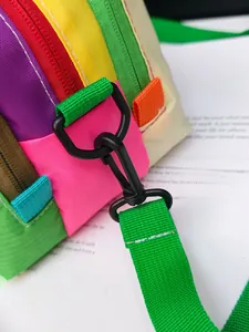 Detail of durable black plastic hook and green woven strap on a multicolor crossbody bag