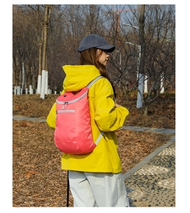Outdoor waterproof pink folding backpack with grey straps shown in a natural park setting