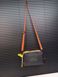 Close-up of waterproof nylon crossbody bag with colorful zippers and orange strap