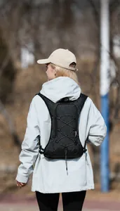 Detail of a lightweight black cycling backpack with bungee cords on a model outdoors