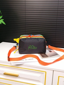 Detail of waterproof nylon crossbody bag with rainbow patchwork and bright orange strap