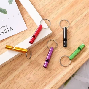 Sifflets de survie en aluminium coloré avec porte-clés sur un fond en bois clair