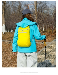 Outdoor sports backpack in yellow waterproof nylon fabric shown on a model in nature