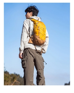 Outdoor hiking backpack in yellow and brown worn by a model against a clear blue sky