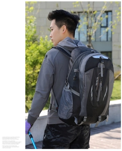 Detail of gray hiking backpack side mesh pocket with adjustable straps and trekking pole