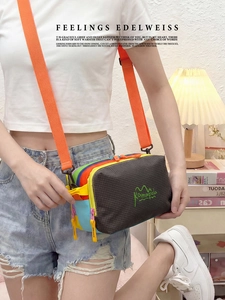 Detail view of multi-compartment crossbody bag with colorful zippers and wide orange strap