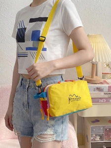 Outdoor crossbody bag in yellow nylon with colorful accents worn by a person