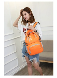 Detailed view of lightweight orange folding backpack with grey zippers and side mesh pockets