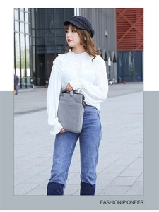 Graue Laptoptasche aus Filz mit Griff und Vordertasche, präsentiert von einem Model
