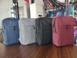 Business laptop backpacks in four colors on desk showing durable fabric and slim front pocket