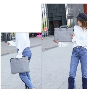 Graue Laptoptasche aus Stoff in der Hand vor städtischem Hintergrund abgebildet