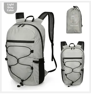 Detail of light grey foldable backpack showing ripstop fabric and mesh side pockets