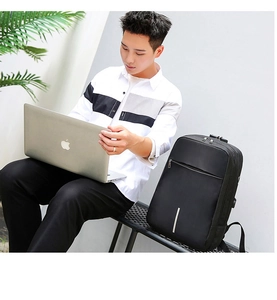 Business-Rucksack mit USB-Ladeanschluss neben einem professionellen Laptop