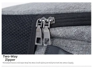 Détail de la fermeture éclair bidirectionnelle et du port USB sur un sac à dos gris