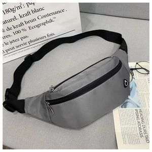 Détail d'un sac banane gris en nylon avec fermetures noires et sangle réglable sur décor