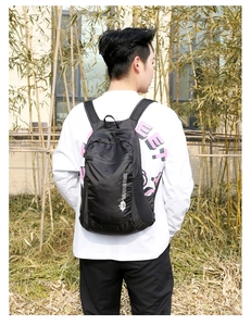 Rear view of a lightweight black folding outdoor backpack on a male model in nature