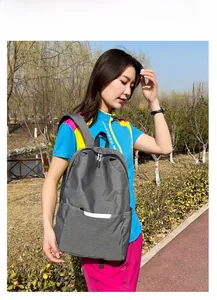 Sac à dos gris réfléchissant porté par un mannequin dans un parc extérieur