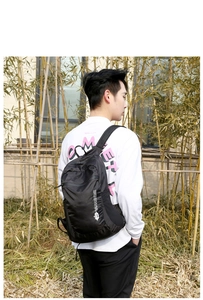 Detail of waterproof black outdoor travel backpack with side mountain logo and shoulder strap