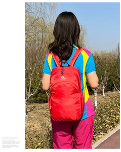 Detail view of a red lightweight outdoor backpack featuring mesh side pockets and adjustable straps
