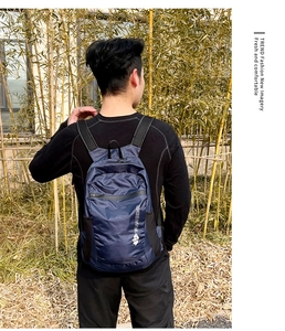 Rear view of a navy blue waterproof nylon backpack with white logo in a bamboo forest