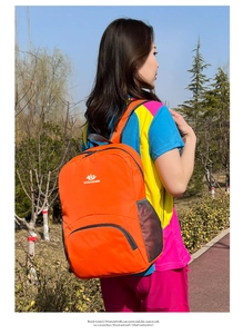 Dettaglio dello zaino outdoor arancione in nylon leggero con logo VANAHEIMR e rete laterale