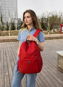 Detail view of lightweight red folding backpack with front zipper pocket in outdoor setting