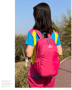 Outdoor view of a waterproof magenta backpack with functional side pockets and logo
