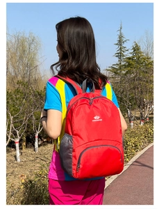 Zaino rosso leggero da esterno con logo VANAHEIMR indossato da un modello nel bosco