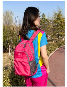 Outdoor lifestyle shot of a lightweight rose red folding backpack with side mesh pockets