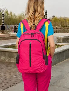 Vista posteriore di uno zaino in nylon fucsia leggero con tasche laterali in rete all'aperto
