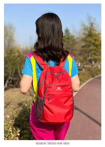 Outdoor shot of a red water-resistant travel backpack featuring side mesh pockets