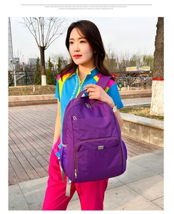 Détail d'un sac à dos violet en nylon avec poche latérale en filet et compartiments zippés