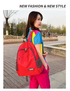 Outdoor view of lightweight red foldable backpack with adjustable straps and side mesh pocket