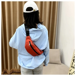 Detailansicht einer Person mit einer leuchtend orangefarbenen Gürteltasche aus Nylon