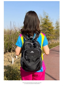 Outdoor shot showing the multi-pocket structure and side mesh pocket of a black backpack