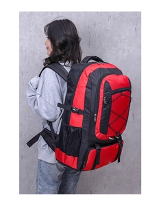 Side view of large red and black waterproof outdoor hiking backpack worn by a female model