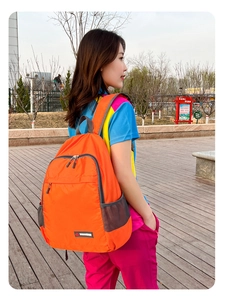 Detail view of the orange waterproof nylon foldable backpack with side mesh pocket and logo
