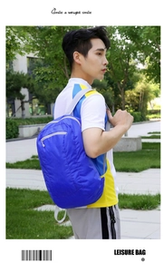 Blue foldable lightweight backpack for outdoor travel worn by a male model in a park
