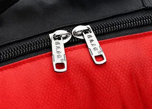 Detail of durable dual metal zippers on waterproof outdoor sports backpack with red texture