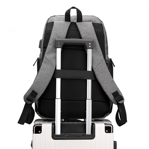 Dark grey business laptop backpack with USB port and luggage strap on a suitcase