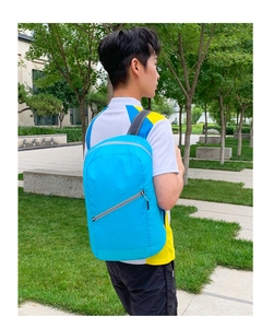 Close-up of light blue foldable backpack with breathable mesh straps and front zipper