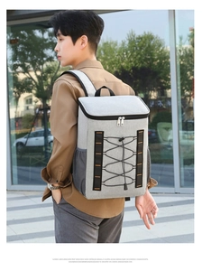 Vista lateral de la mochila térmica gris grande con costuras naranjas en un modelo masculino