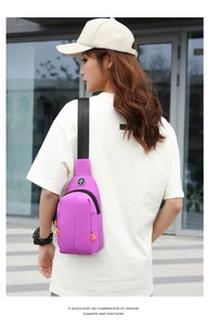 Detailed close-up of a purple waterproof chest bag with orange zipper pull tabs for outdoor