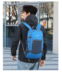 Blue and grey foldable outdoor backpack shown on a model during a hiking activity