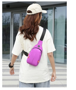 Detail of purple waterproof oxford chest bag with orange zippers worn by outdoor model