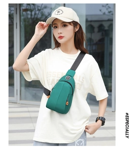 Outdoor street style view of a green waterproof nylon chest bag with orange zipper pullers